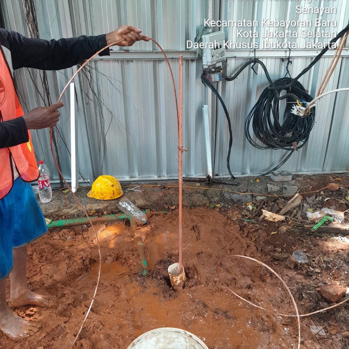 Pekerja memasang batang grounding (pembumian) di tanah