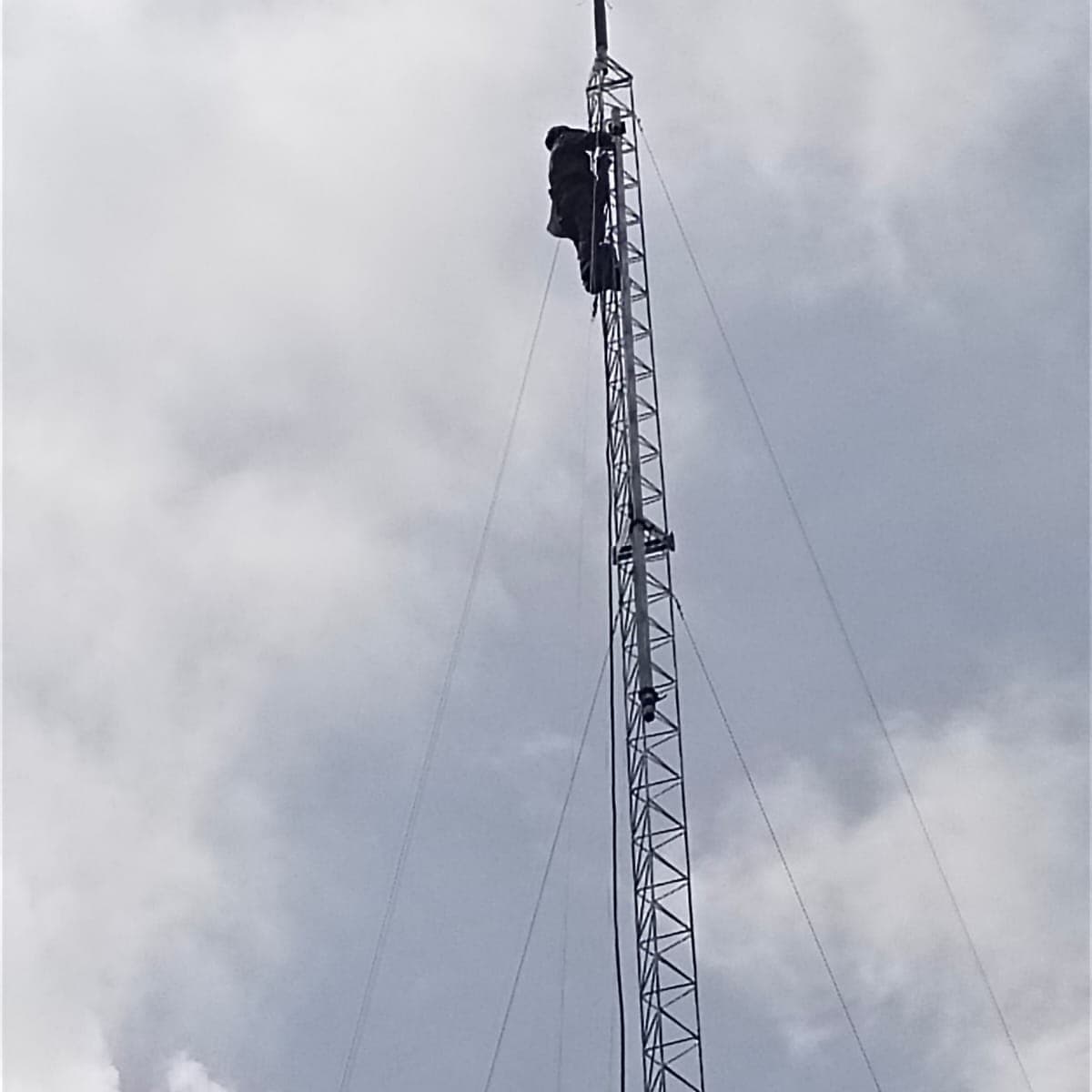 Teknisi naik tower rangka besi untuk memasang penangkal petir